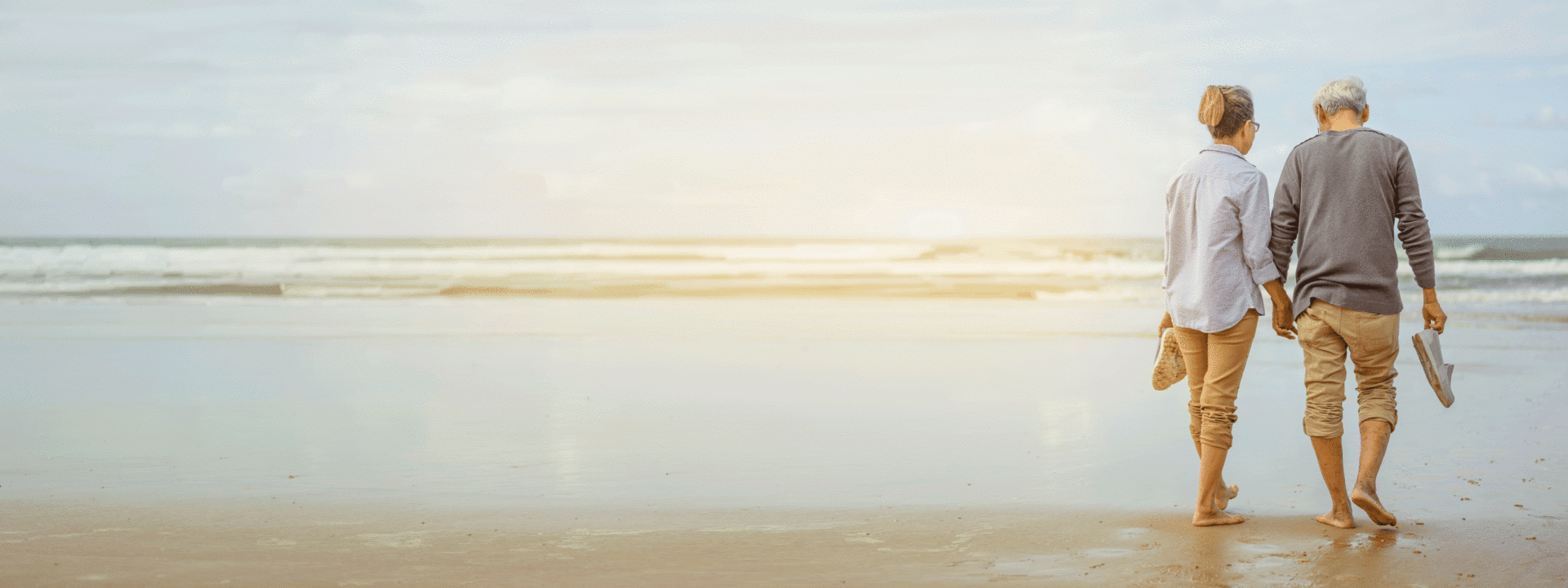 Mature couple walking on beach holding hands